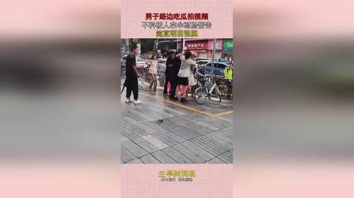 男子路边吃瓜拍视频被拿伞警告